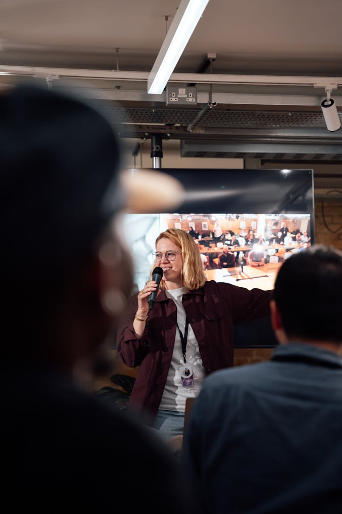 Woman speaks at a seminar in London with an engaged audience. Indoor setting.
